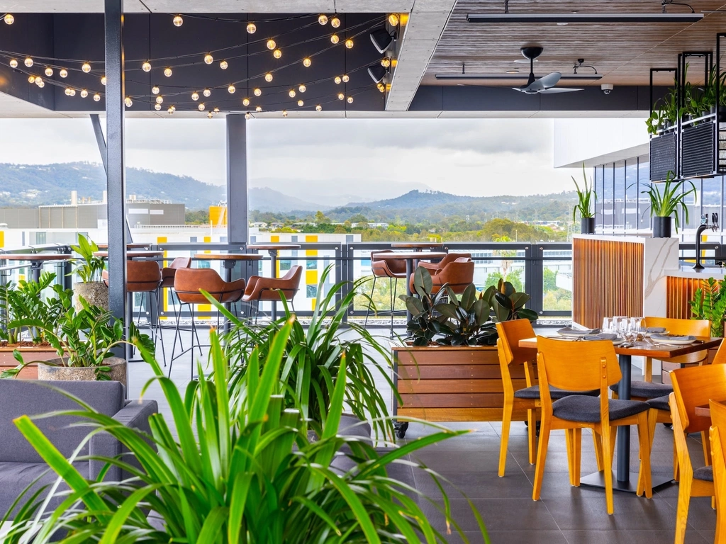 Rooftop area with lounges and tables, festoon lights and hinterland views