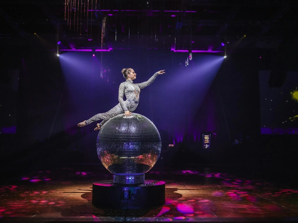 Giant Mirror Ball with performer on top posing with her arm out