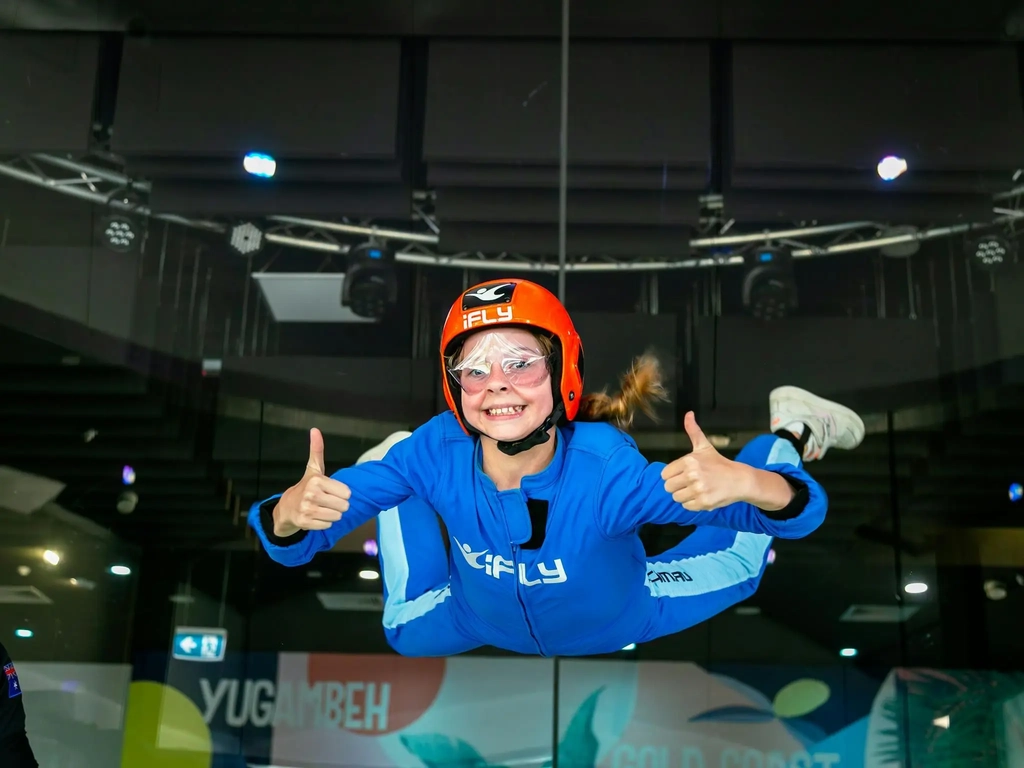 Young girls gives the thumbs up while flying for the first time.