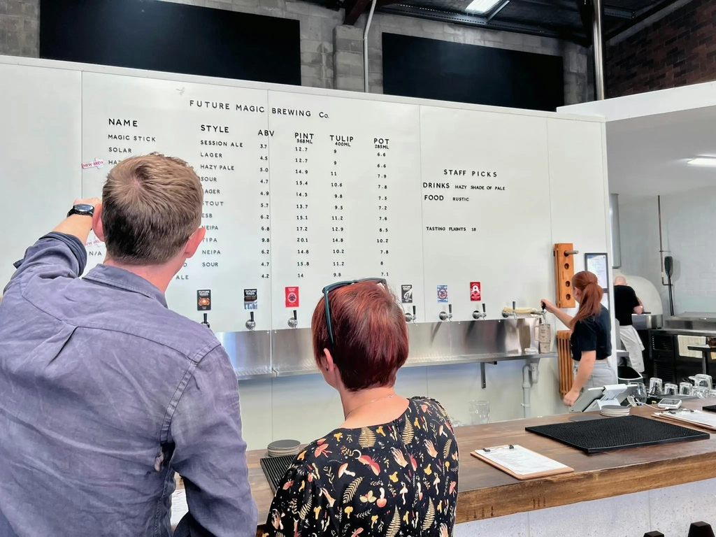 Two people at the bar looking at the menu to order a beer paddle at Future Magic Brewing Co.