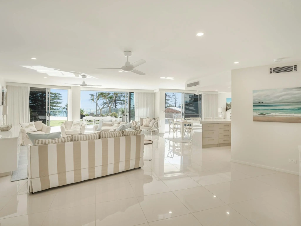Inviting lounge with tan and white striped sofas, high-gloss tiled floors, and expansive oceanview