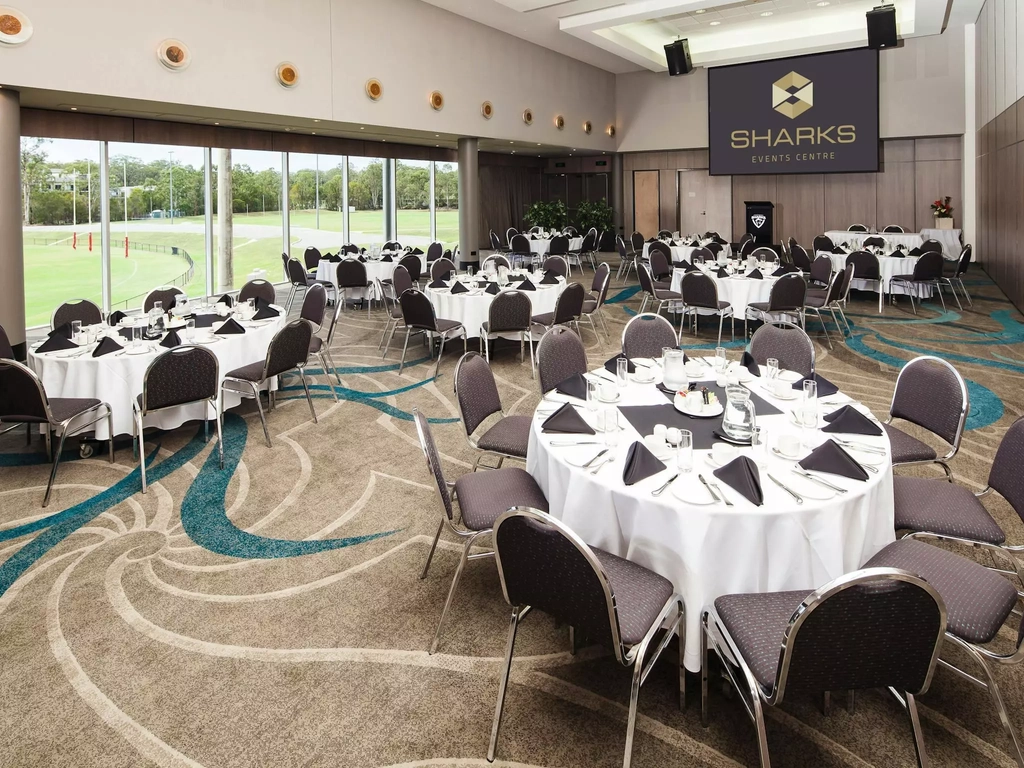 A function room prepared for a corporate breakfast with tables and chairs arranged