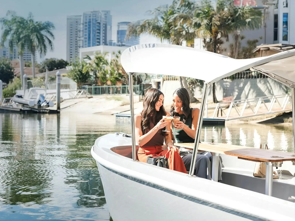 Two guests relaxing on a GoBoat cruising through the waterways at Isle of Capri on the Gold Coast.