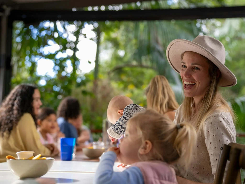 Children and caregivers sharing time together in an outdoor cafe dining area.