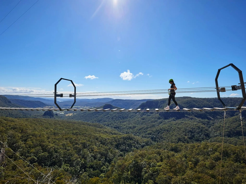Woman walking across Via Ferrata at Happitat Adventure Park