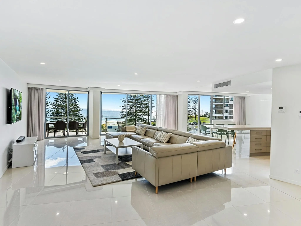 Stylish lounge featuring a leather chaise lounge, high-gloss tiled floors, and stunning ocean views