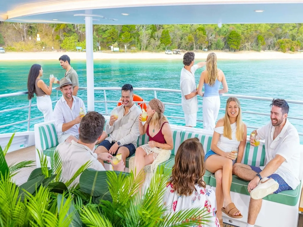 Guests relaxing with a cocktail onboard the See Moreton vessel, enjoying the sea view
