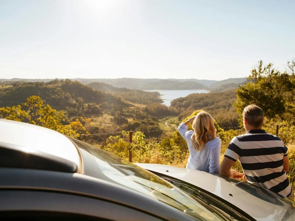 A couple gazing at a sunny horizon overlooking a lake
