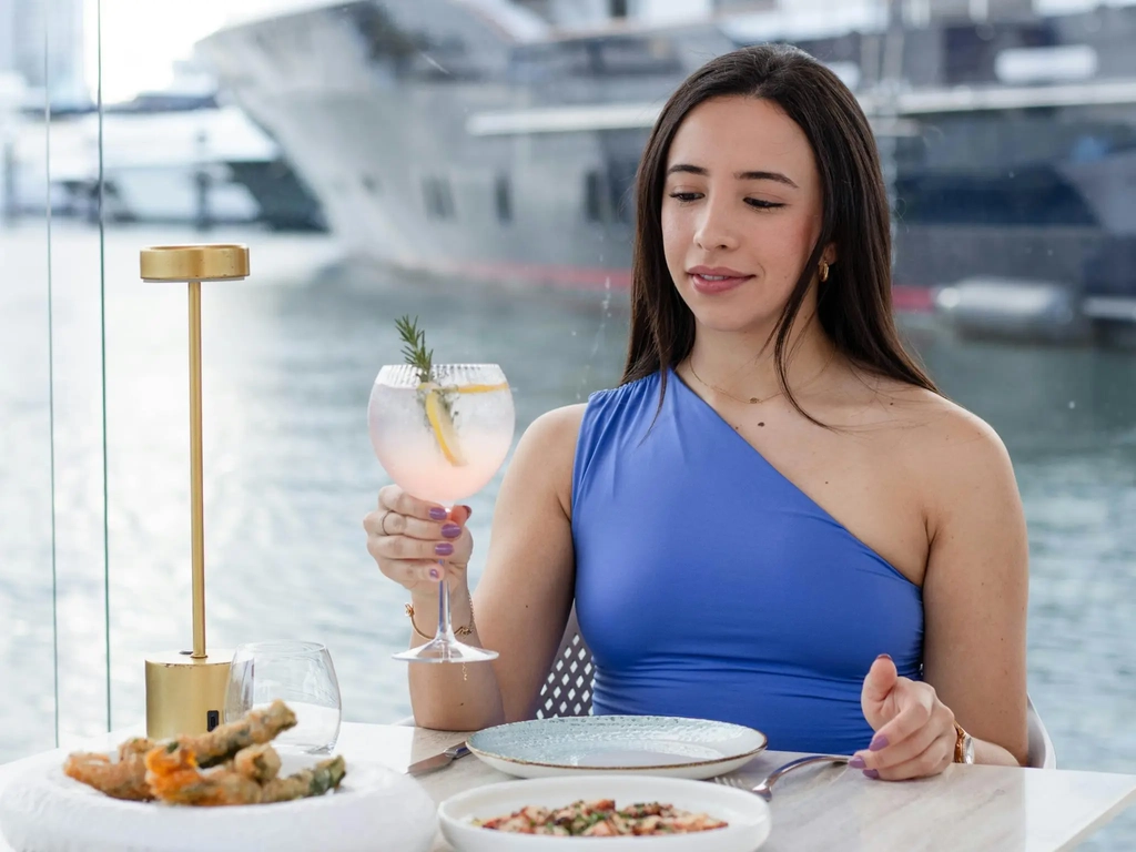 Diner enjoying a glass of wine at MĀRE overlooking the marina