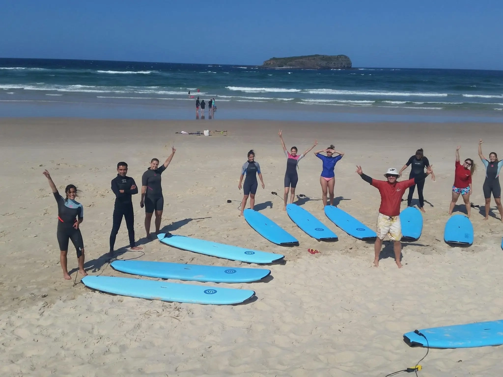 Excited surf students gather on the beach with their boards, ready for an unforgettable day.