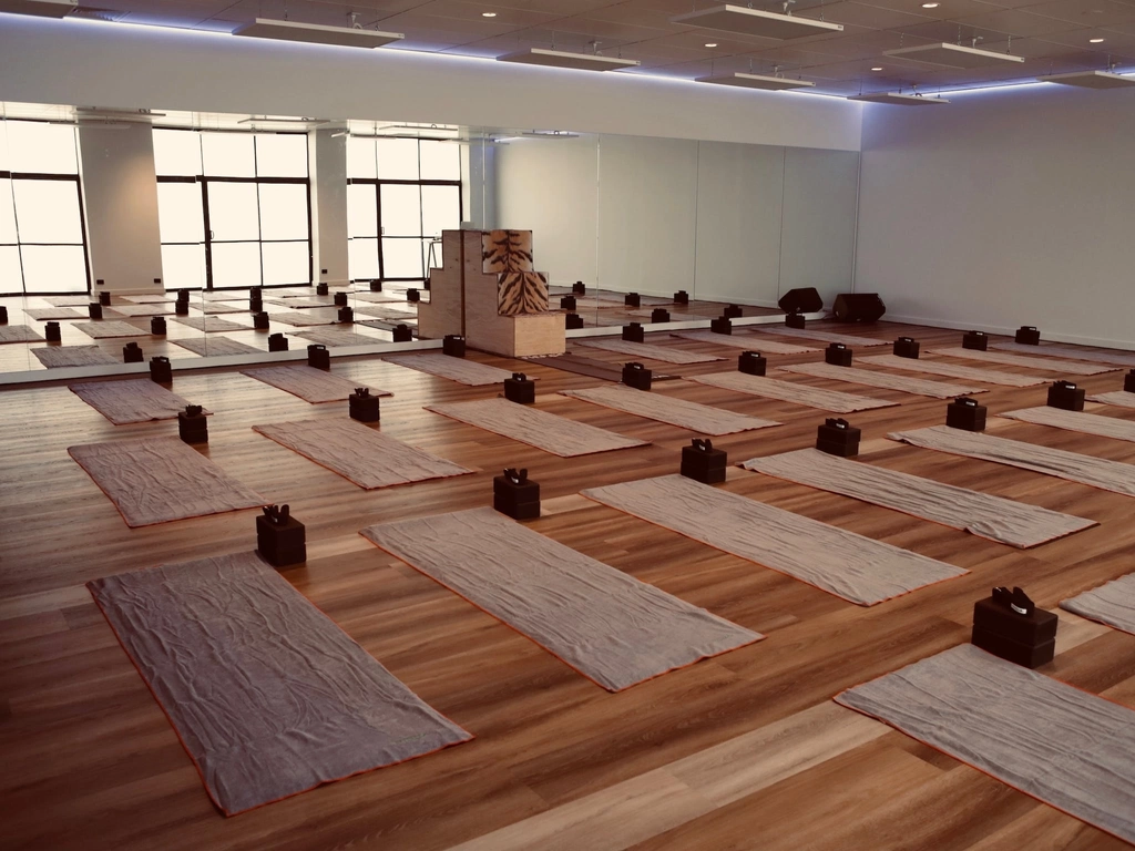 Yoga Studio with full mirrored wall, wooden floor, yoga mats arranged.