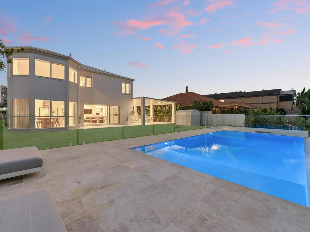 Twilight view of a waterfront home and swimming pool at Whitesands by Aryve, Robina