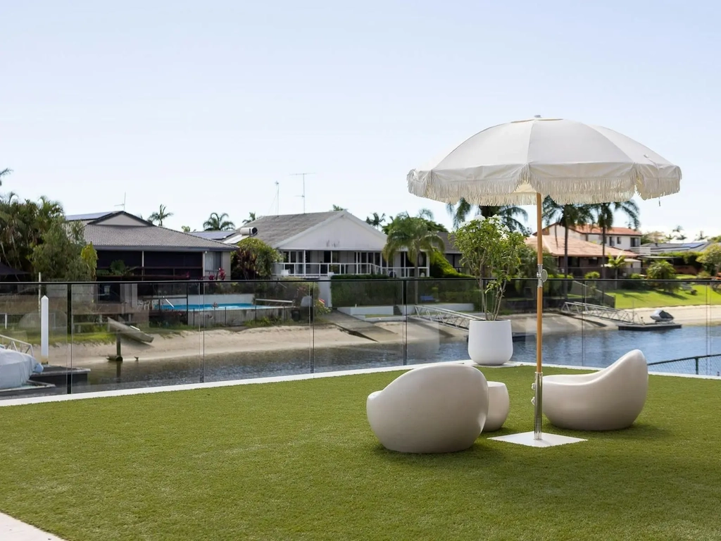 Level lawn running to canal water behind glass fencing