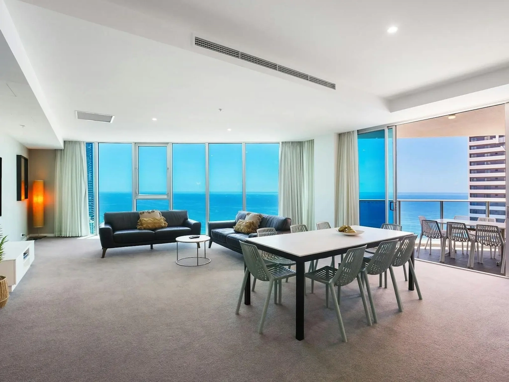 Lounge room of a 4-bedroom apartment at Hilton Surfers Paradise with a view of the blue sea behind