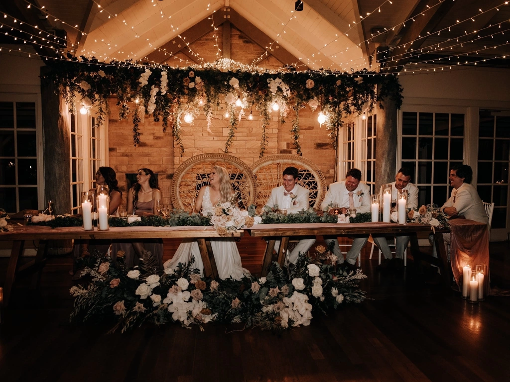 A romantic bridal table endorned with fresh florals arrangements, candlelight and hanging greenery