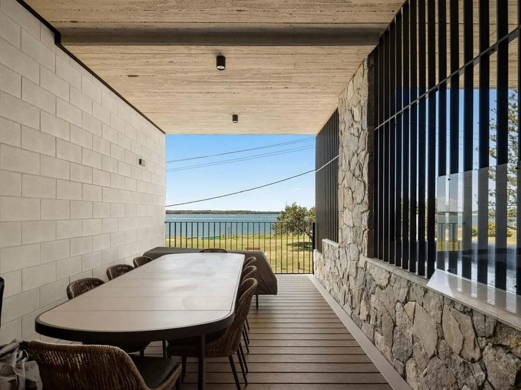 Covered terrace with a long dining table overlooking the Gold Coast Broadwater