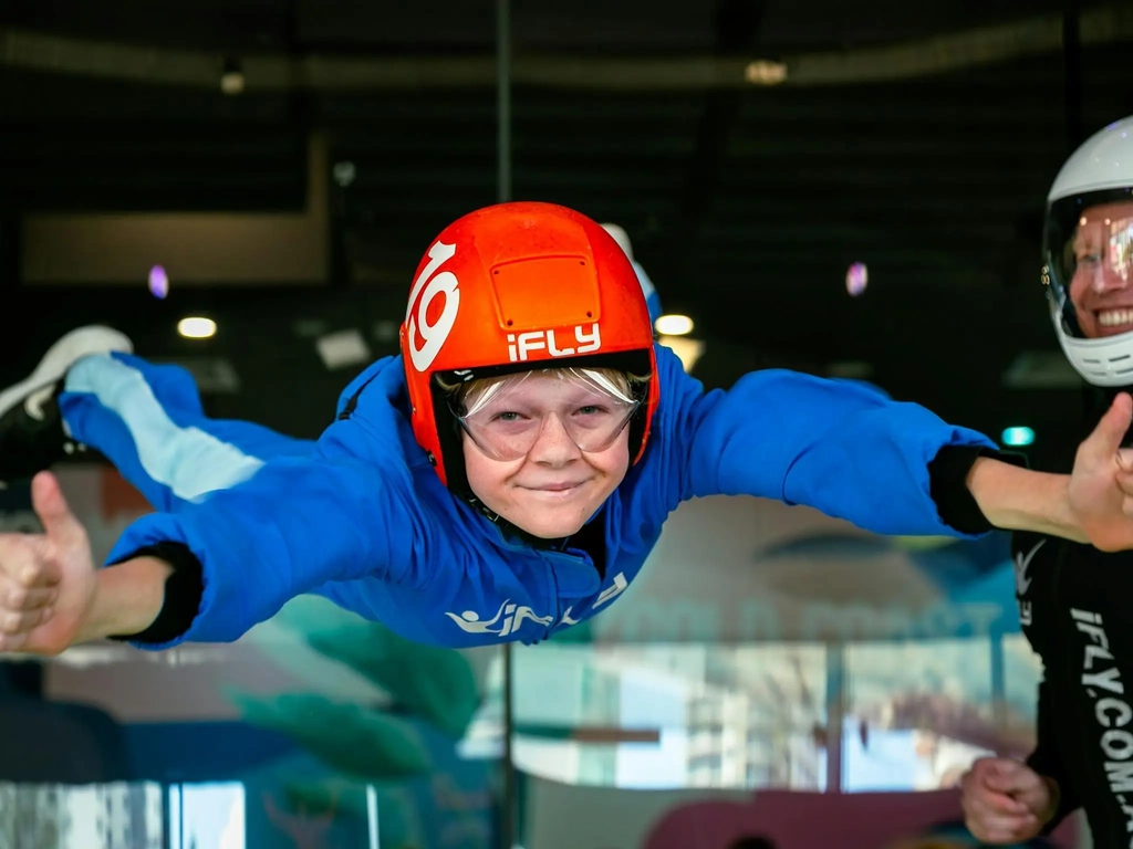 Close up of young boy with thumbs up . Smiling instructor in the background.
