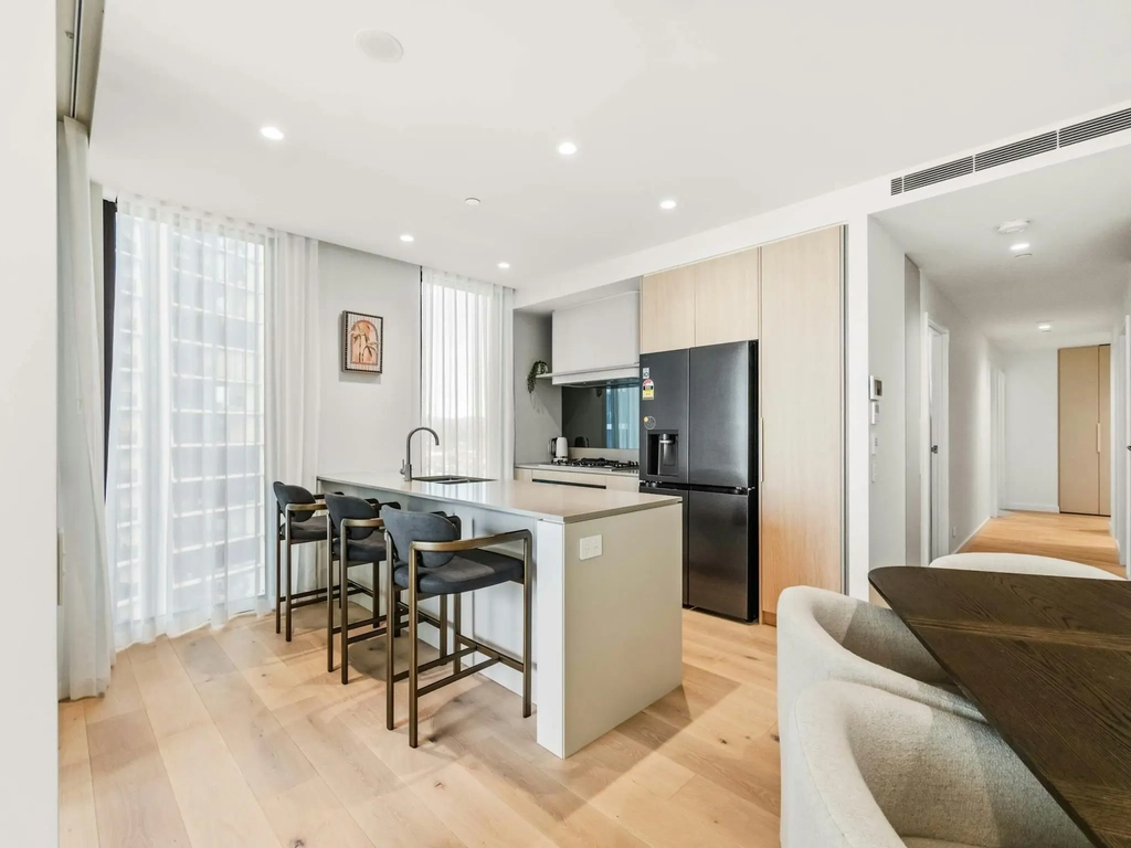 Modern apartment kitchen with a stone island bench, bar stools and gas cooktop