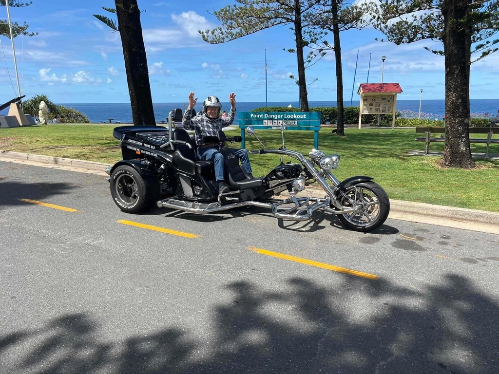Image shows trike with one passenger in front of the beach.