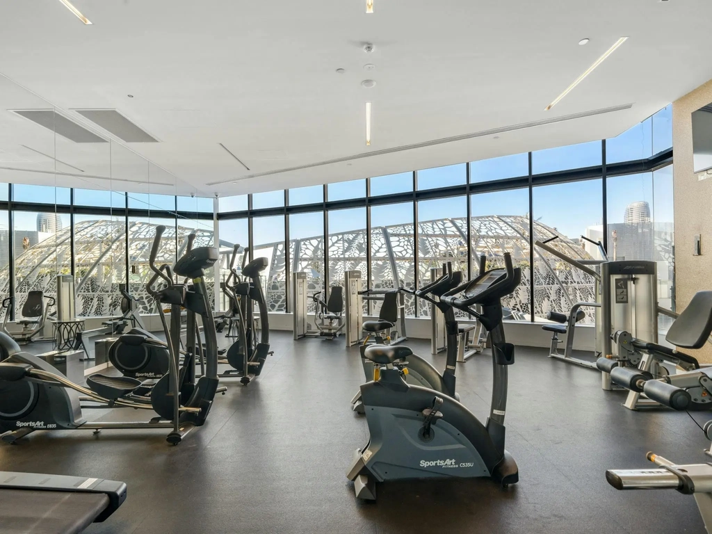 Gymnasium with cardio equipment and full height windows over the coast.