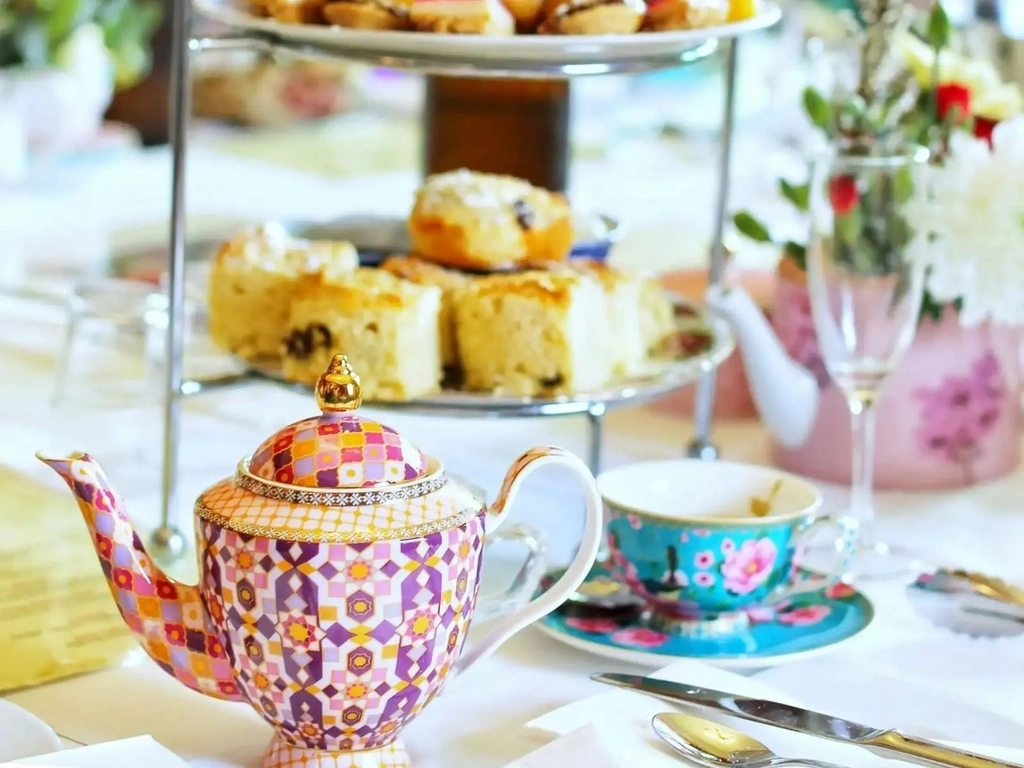 close up of a high tea with colourful teapot cups and scones