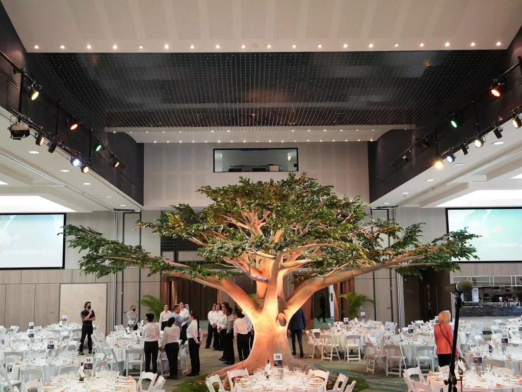 A tree installation inside a function room, with tables and chairs prepared for an event