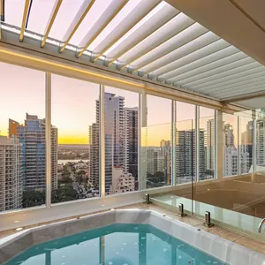Private rooftop spa enclosed in glass under a louvred roof, city towers at sunset