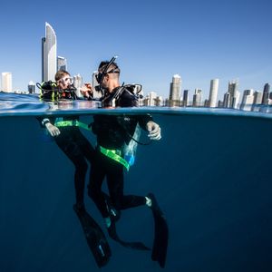 two scuba divers with the Gold Coast city building skyline behind them
