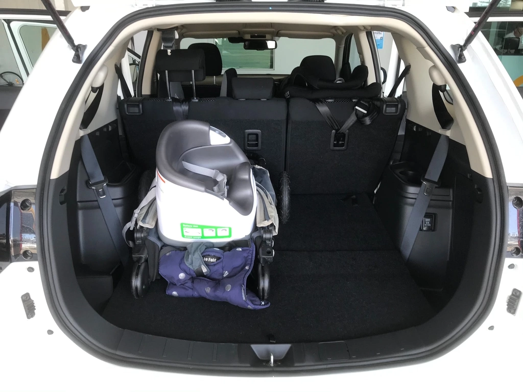 A folded pram and feeding seat in the boot of a white SUV
