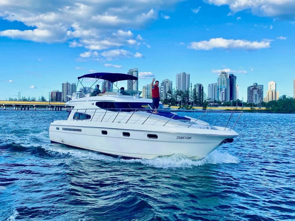 Luxury yacht on clear blue water with city skyline in the background – Broadwater, Gold Coast.