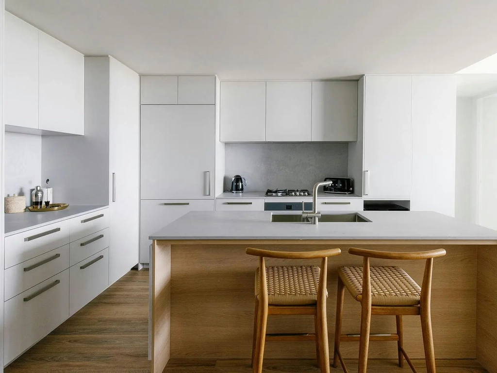 Sleek Kirra Point kitchen with stone island bench, modern appliances, and timber bar stools.
