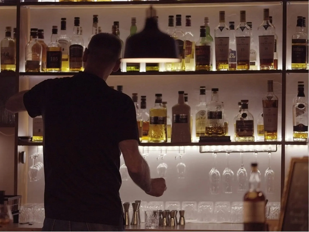 Uwe owner of whisky lounge pouring drinks at the bar