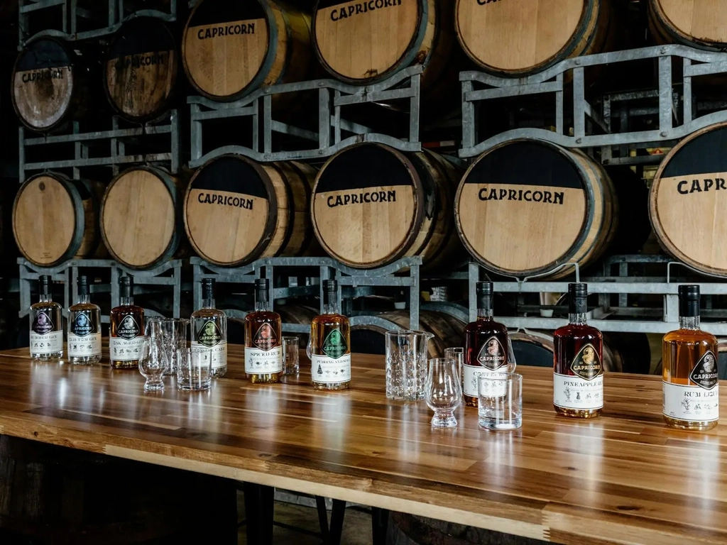 Various rums from our tours and tastings displayed on a table in front of our ageing barrels.