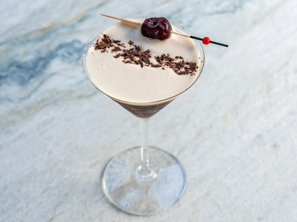 Espresso martini with chocolate shavings and a cherry garnish on a marble bar