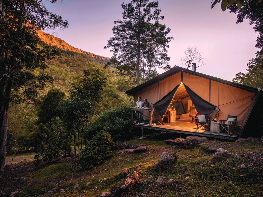 Romantic couple enjoy the change in light from the safari tent deck as night falls.