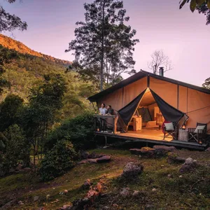 Romantic couple enjoy the change in light from the safari tent deck as night falls.