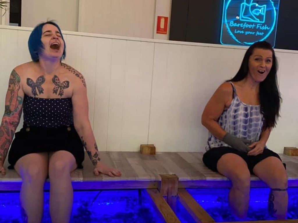 Two ladies laughing as they have a fish spa at Barefoot Fish