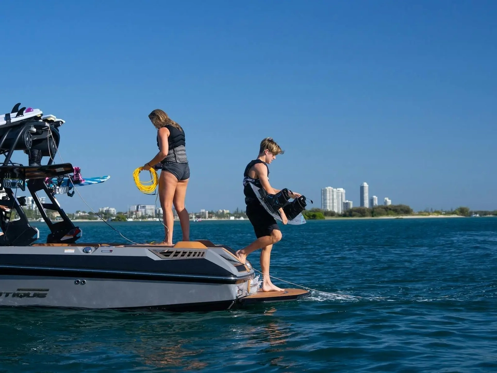 Two riders on the back of the boat preparing to hit the water