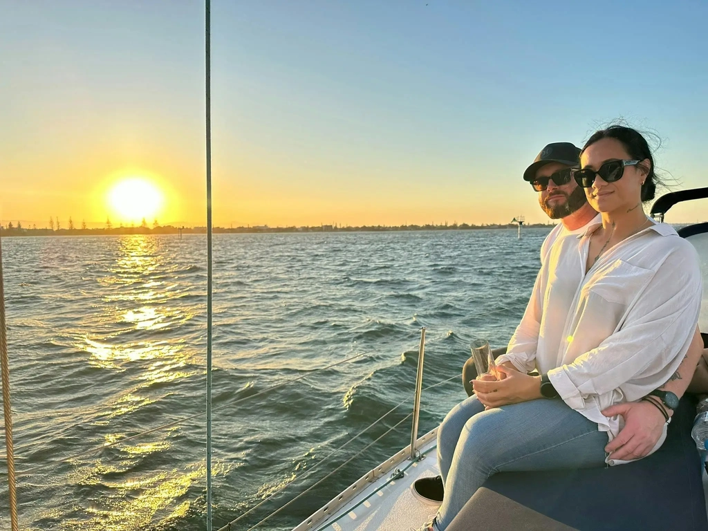 Couple sitting on deck Sun Sailing yacht watching the sun set on the Gold Coast Broadwater.