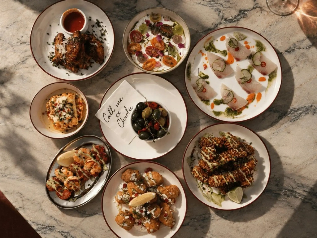 Share plates of wings, kingfish crudo, olives, prawns and haloumi on a marble table