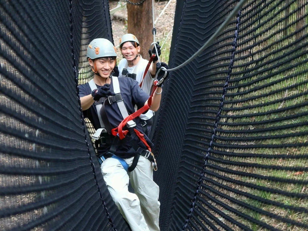 2 Gentleman climbing through a net game on the high ropes adventure park