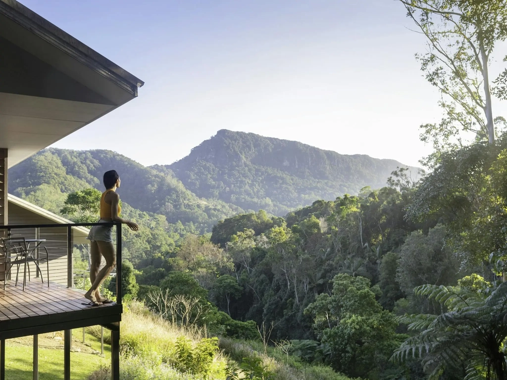 Woman standing on balcony looking out over view of Currumbin Valley