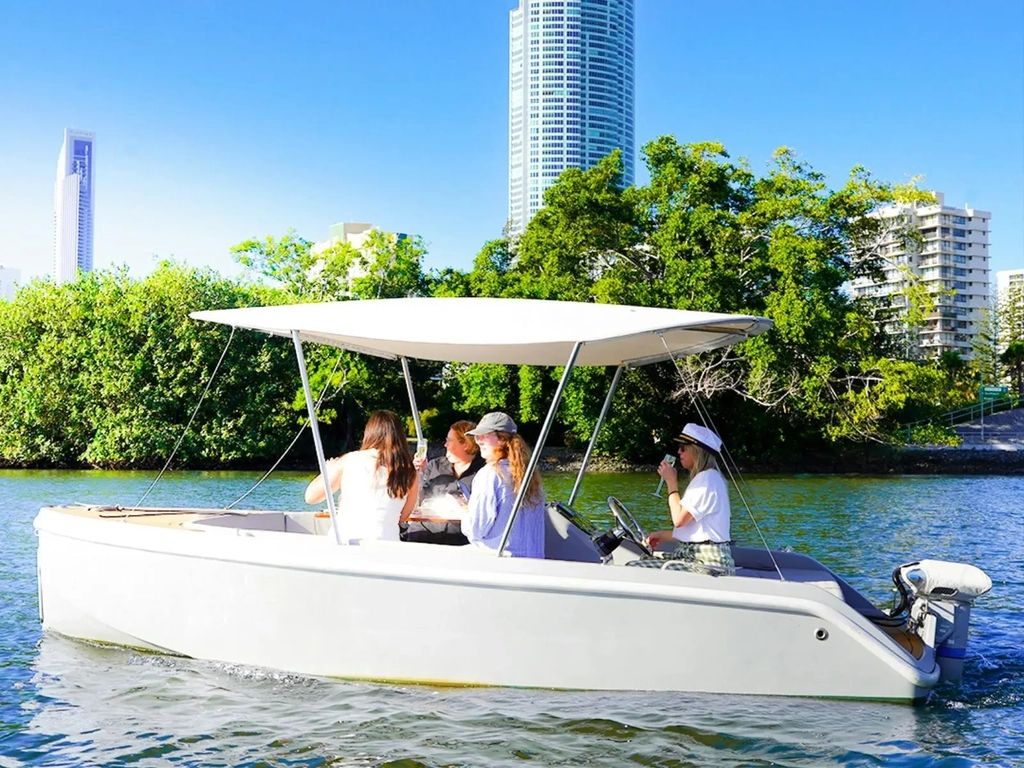 Group of guests relaxing aboard a self-drive GoBoat with Gold Coast skyline views in the background.