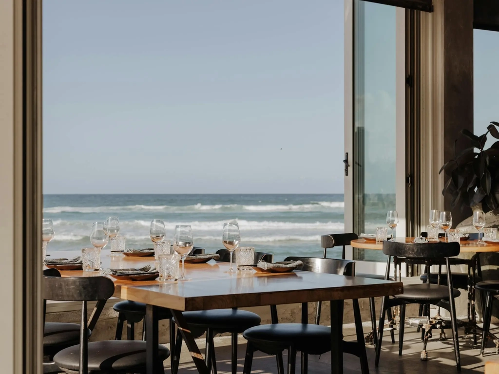 Tables at Rick Shores looking out onto the ocean through the open windoes