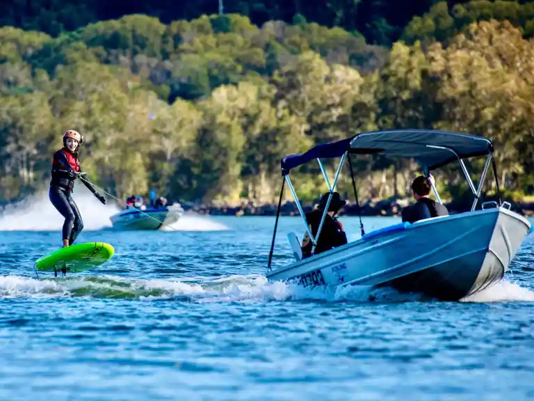 A Foiling Australia boat toeing a beginner female student that is learning foiling