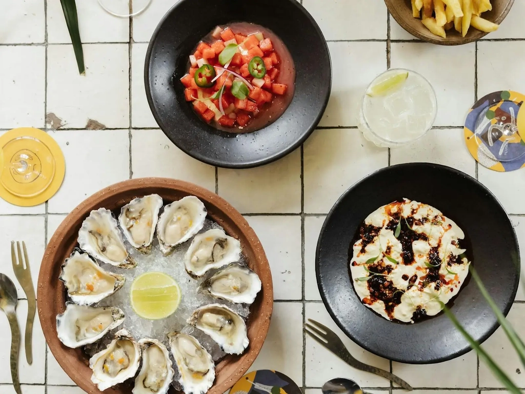 Oysters and a spread of food on a white tiled table