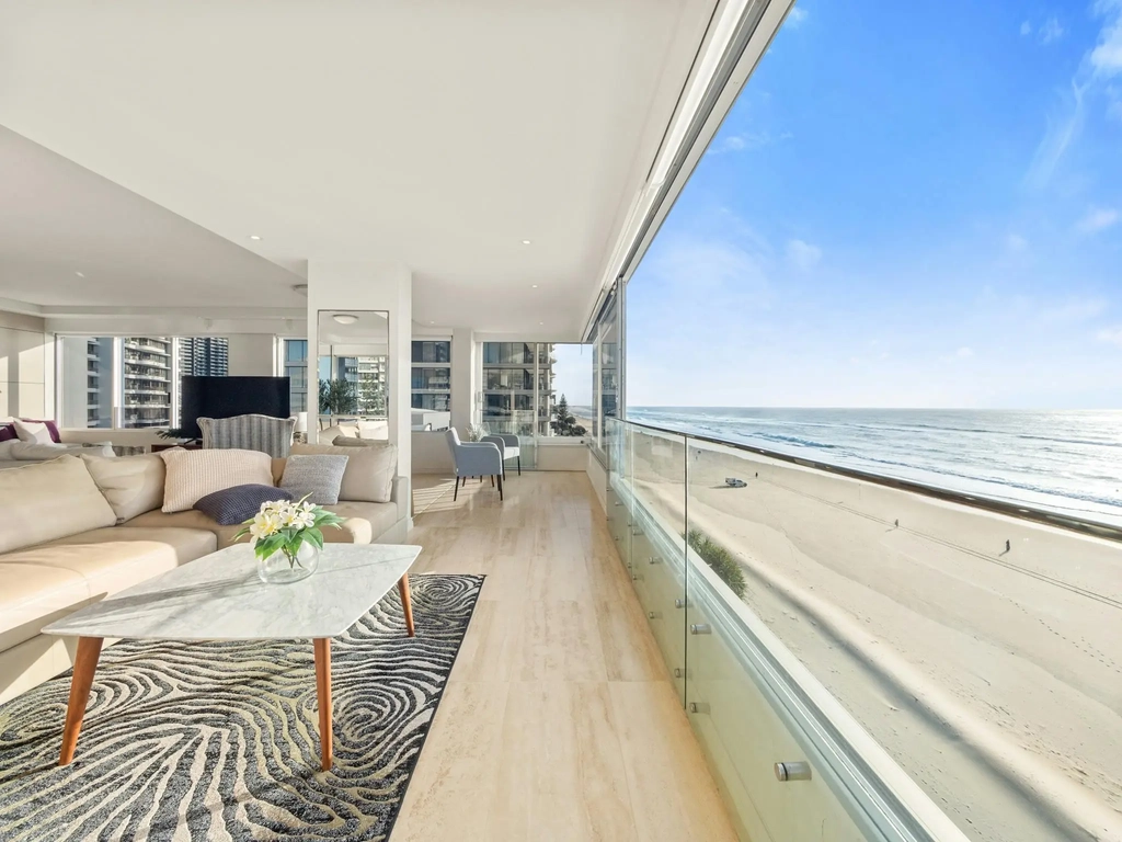 Open-plan living area with the sand and surf directly below the glass