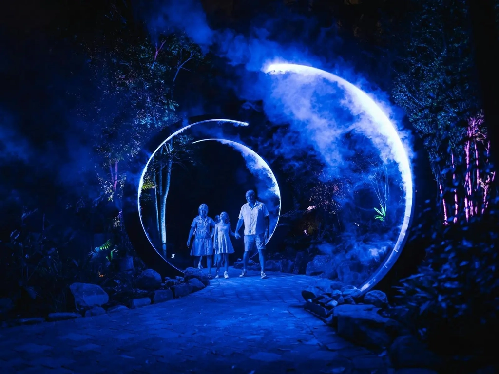 Family walking through blue illuminated archways with smoke effects.