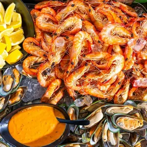 Ocean king prawns on a platter next to mussels and cocktail sauce