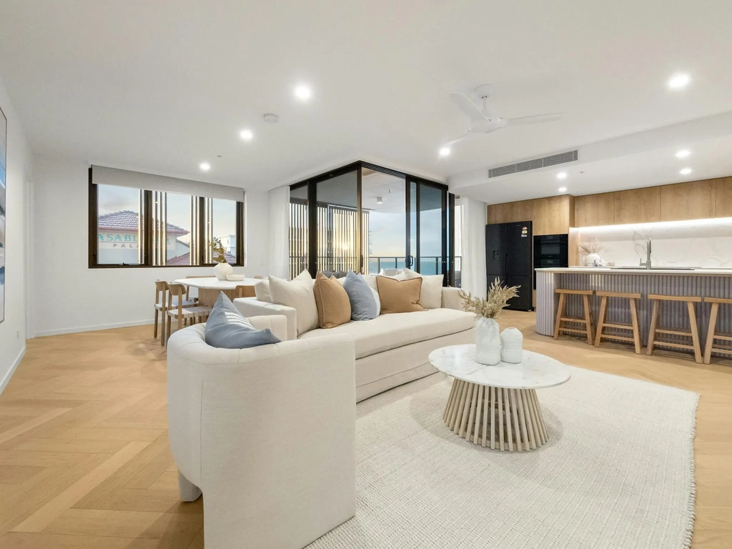 Open plan living and dining with sofa, dining table, kitchen and oak flooring